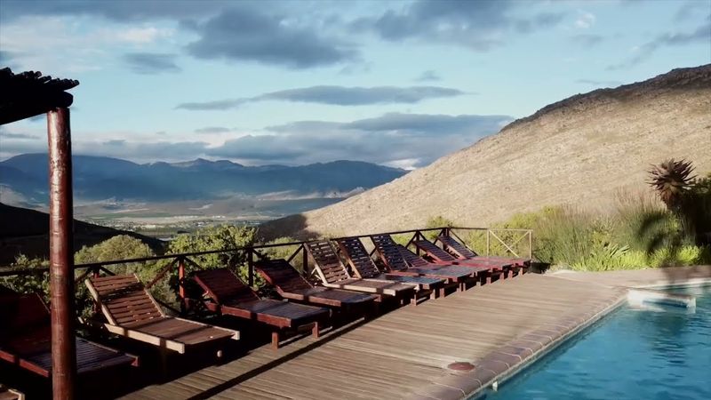 A frame from the resort’s film: the pool deck and loungers, looking over the valley to the mountains