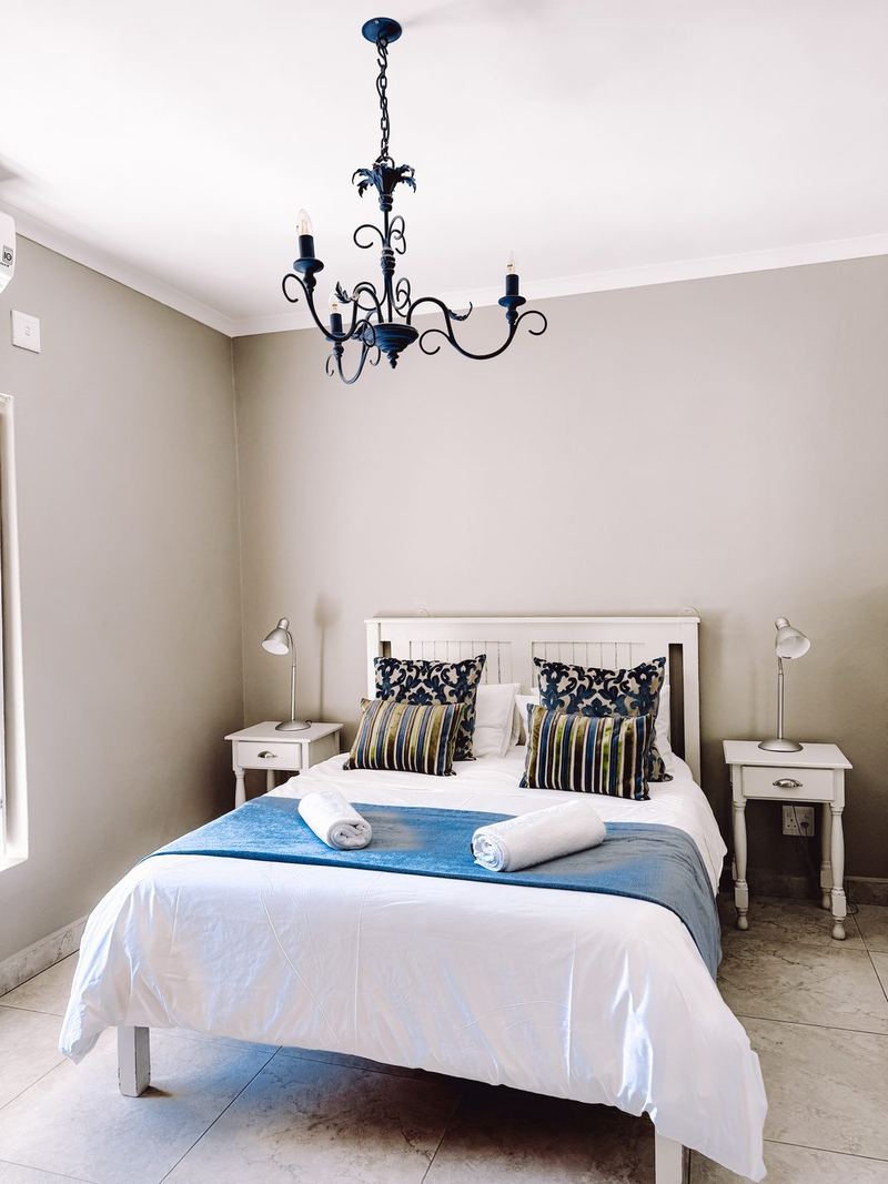 A bright bedroom at The Baths with a double bed, a chandelier and bedside tables.