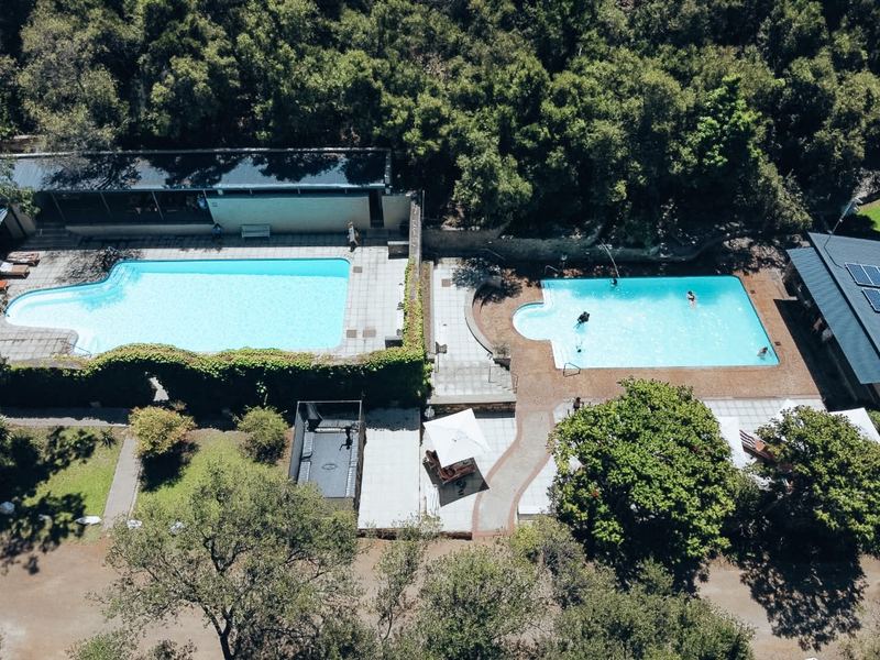 Aerial view of the hot and the cold swimming pool at The Baths, with loungers and trees around them