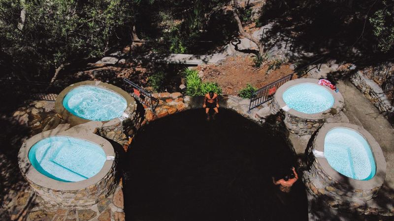 Four round stone-walled hot pools seen from above at The Baths, set into the rock in the shade.