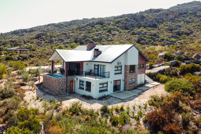 Aerial view of Spekboom, a two-storey house on Wolfkop Nature Reserve, in fynbos below a rocky ridge.