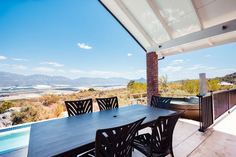 The covered deck at Spekboom with a long table and a view down to the valley.