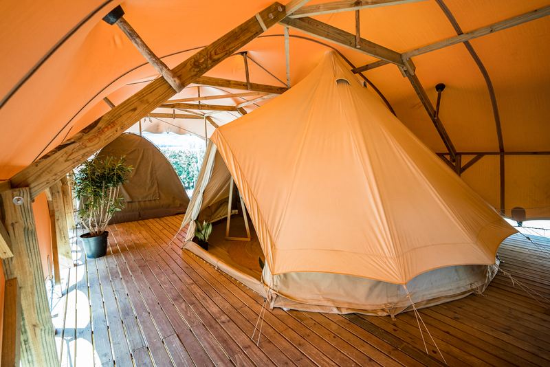 Inside a villa: a bell tent pitched on the wooden deck under the canvas roof.